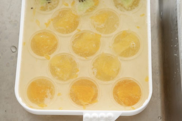製氷皿に寒天液とフルーツを入れる